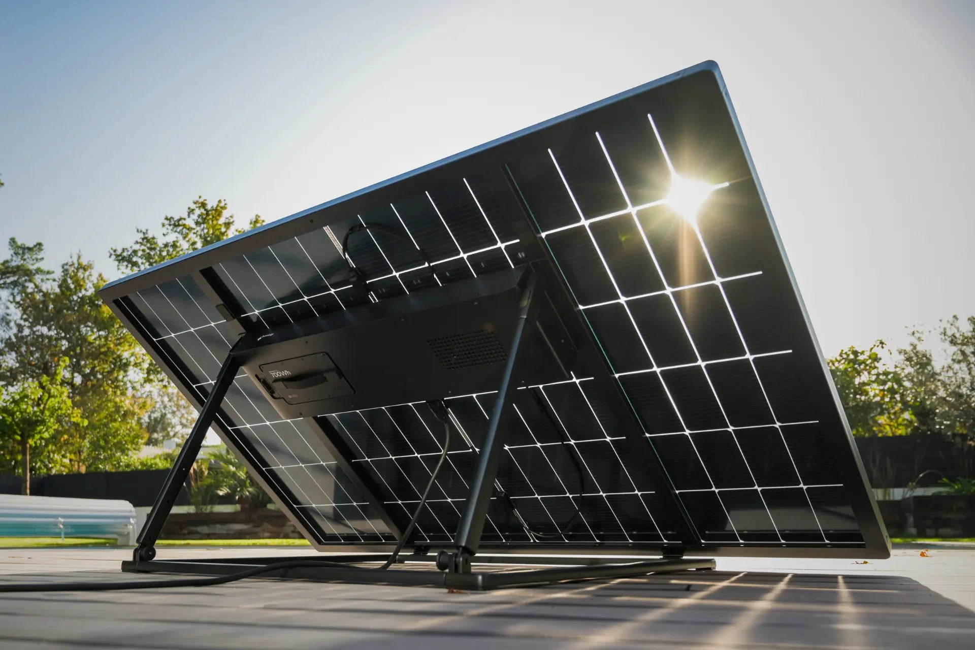 Panneau solaire photovoltaïque plug and play avec batterie posé au sol sur terrasse avec rayons de soleil de la marque Sunology PLAYMax