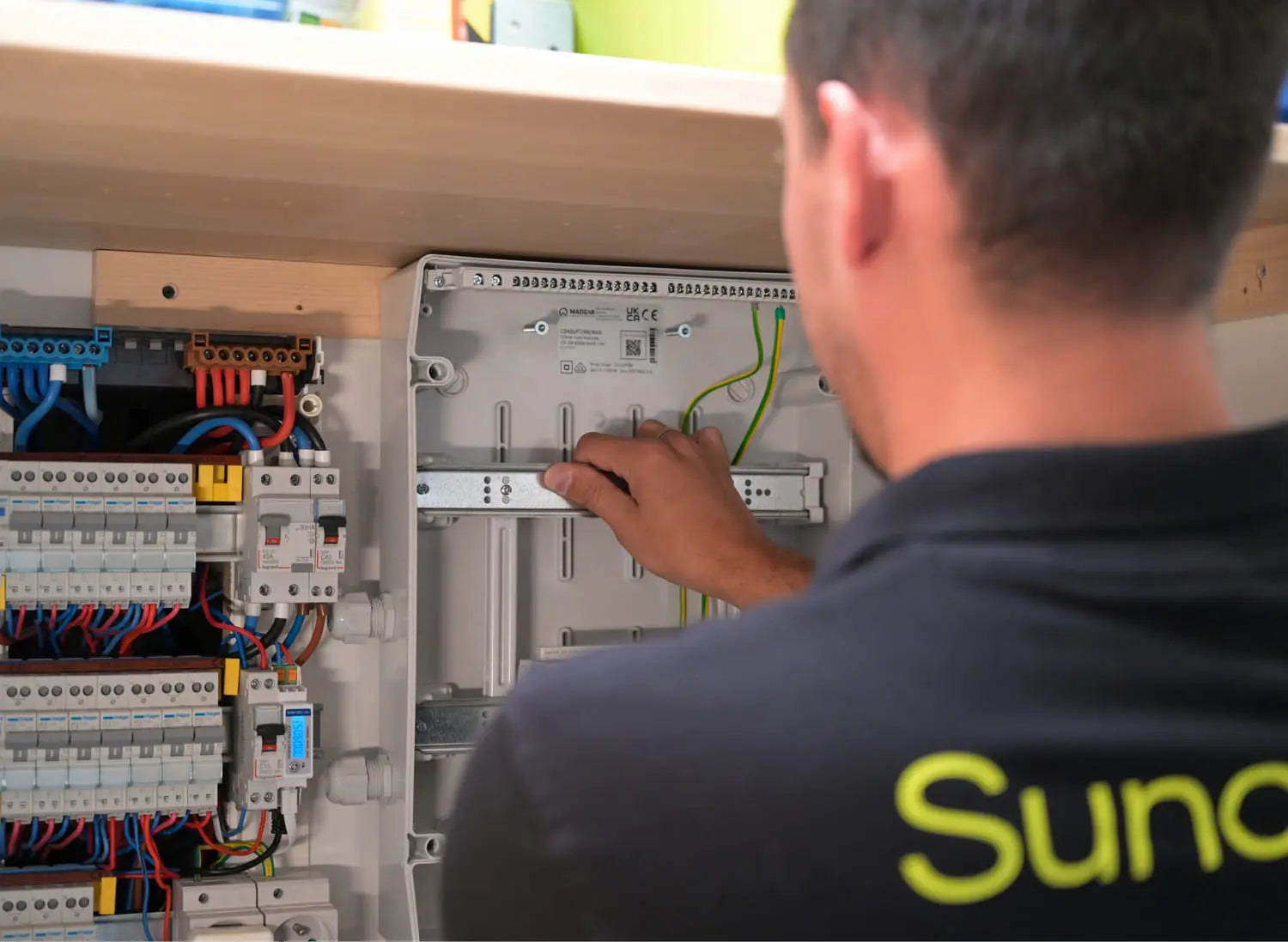 Installateur Sunology en intervention, ajustant les connexions dans le tableau électrique du client — finition de l’installation solaire photovoltaïque en toute sécurité.